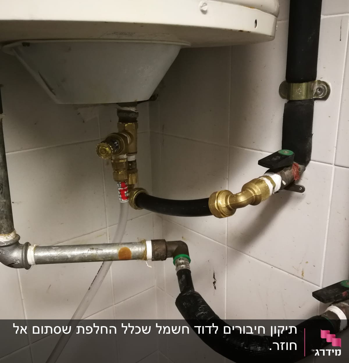 צינורות מתכת וברזים מתחת לדוד מים